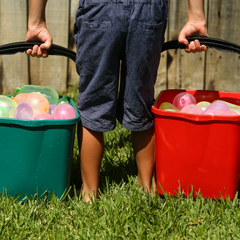Boy carrying two buckets of Water Balloons